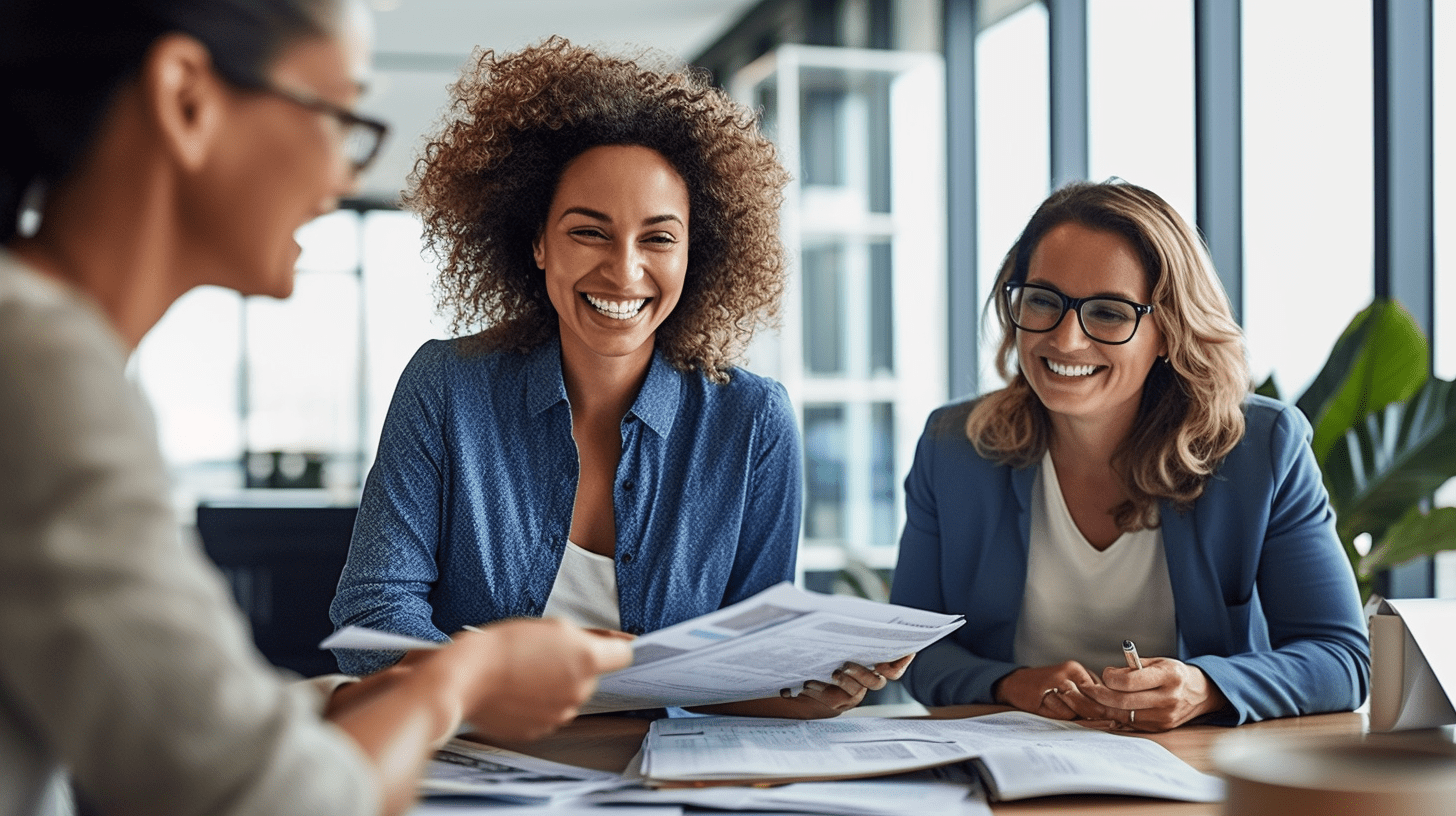 The Power Of Top Real Estate Speakers To Unlock Real Estate Success 3 Two professionals reviewing documents at a table with a colleague