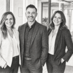 Three professionals standing together in a bright residential interior.